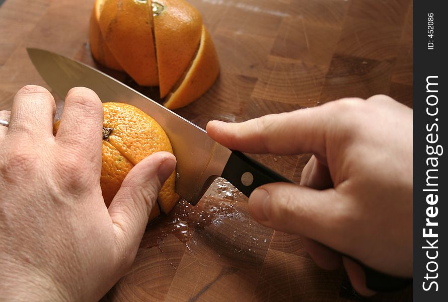 Hands slicing oranges on wooden cutting board. Hands slicing oranges on wooden cutting board