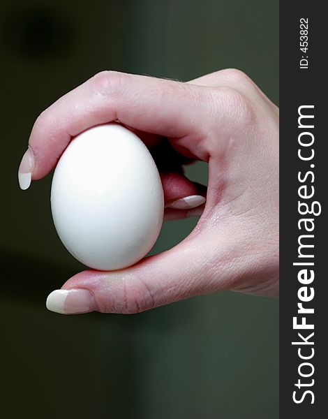 Hand holding an egg up close showing the shape