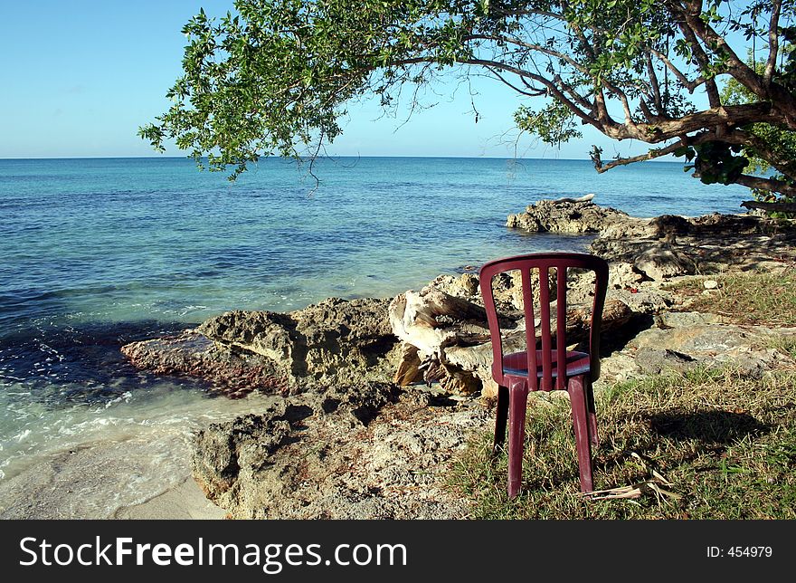 A chair on a rocky shore overlooking the ocean. A chair on a rocky shore overlooking the ocean