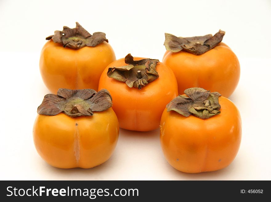 Five persimmons arranged as on dice, on a white surface and background. Five persimmons arranged as on dice, on a white surface and background