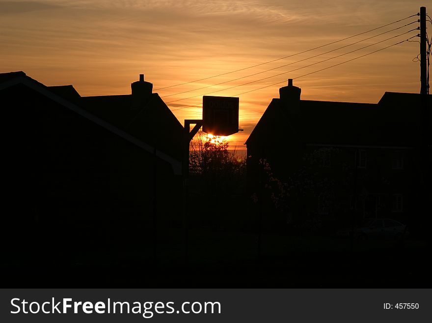 Basket ball ring silhoueted in build up housing area. Basket ball ring silhoueted in build up housing area