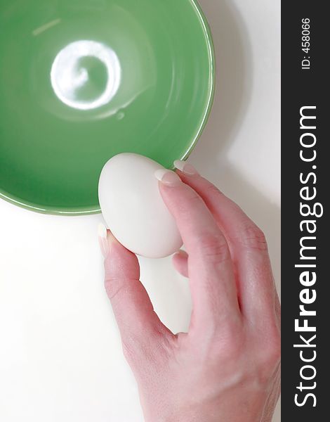 Hand holding an egg over green bowl