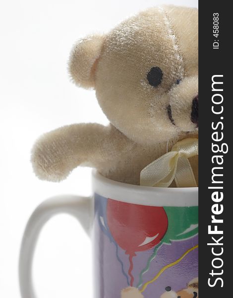 Small teddy bear in a coffee cup up close on white