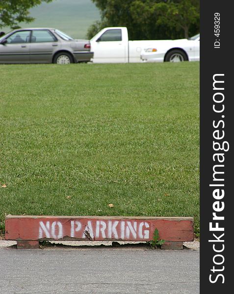A wooden marker warns against parking near the grass. A wooden marker warns against parking near the grass.
