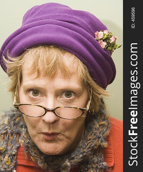Beauitful older woman with a fun expression wearing a purple hat and red sweater. Beauitful older woman with a fun expression wearing a purple hat and red sweater.
