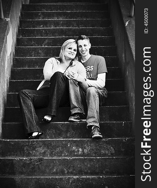 Young couple sharing a tender moment on city stairs. Black and white. Young couple sharing a tender moment on city stairs. Black and white