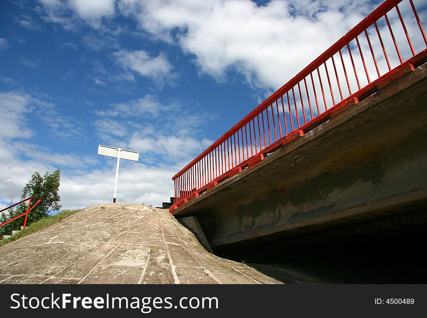 The bridge with a red handrail against the solar sky.