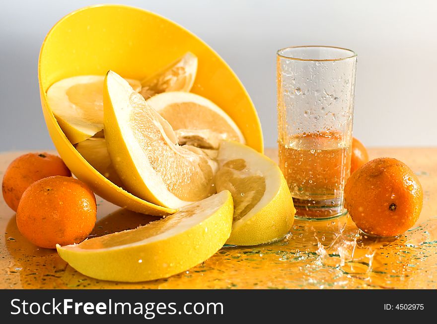 Citruses and glass of juice on yellow,fruit