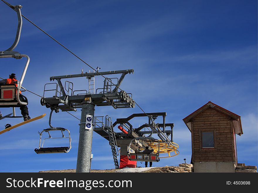 The arrival of a ski lift chairs with a blue sky on background. The arrival of a ski lift chairs with a blue sky on background