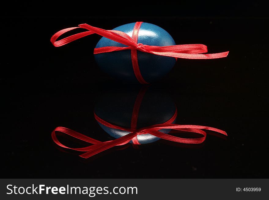 The blue Easter egg is standing with red bow