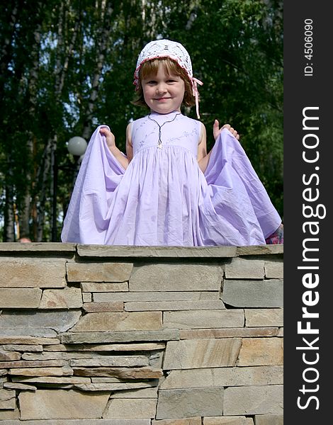 Child in gown standing on wall, stone