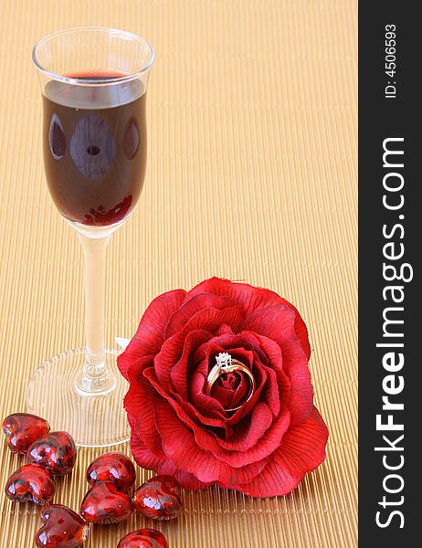 Small after-dinner wine glass with a red rose with a ring in it. Small after-dinner wine glass with a red rose with a ring in it