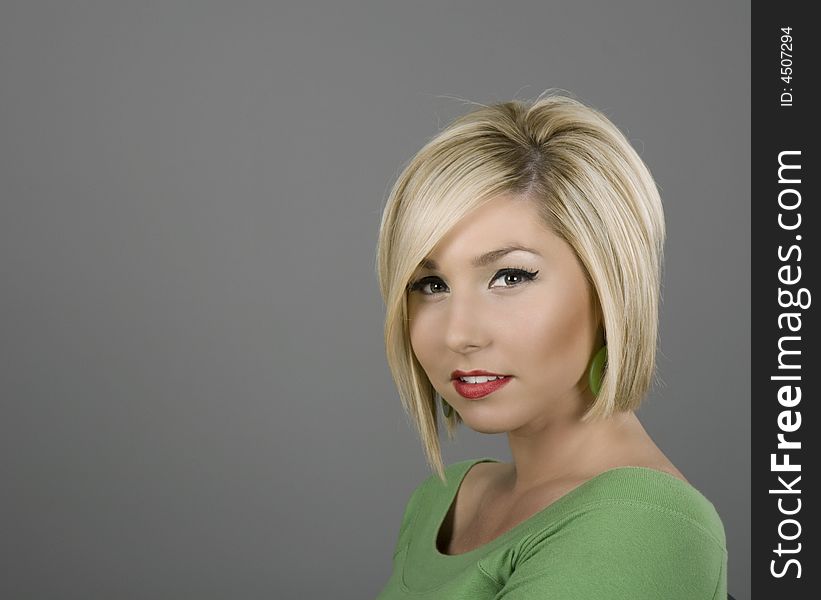 A blonde in a green blouse with a slight smile. A blonde in a green blouse with a slight smile