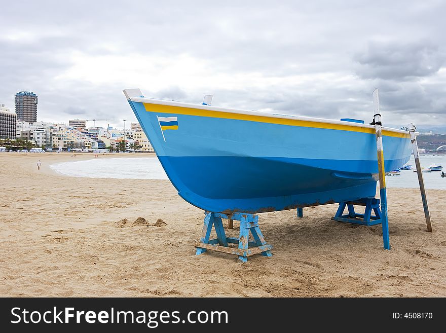 Old fish-boat on sandy beach on a cloudy day