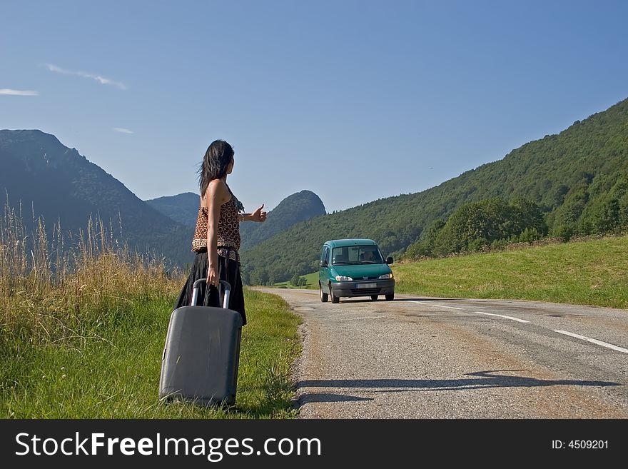 Woman on a mountain road making of hitch-hiking. Woman on a mountain road making of hitch-hiking