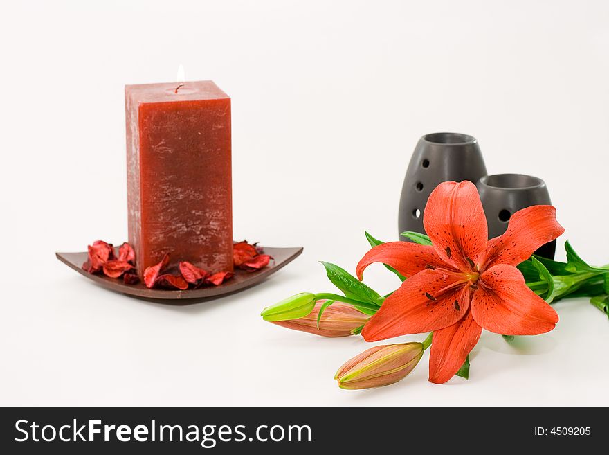 Red lily, red scented candle and black oil burner isolated on white background. Red lily, red scented candle and black oil burner isolated on white background.