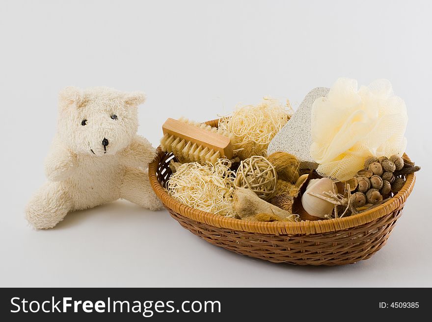 Teddy bear, personal care items and decorations in a basket isolated on white background.