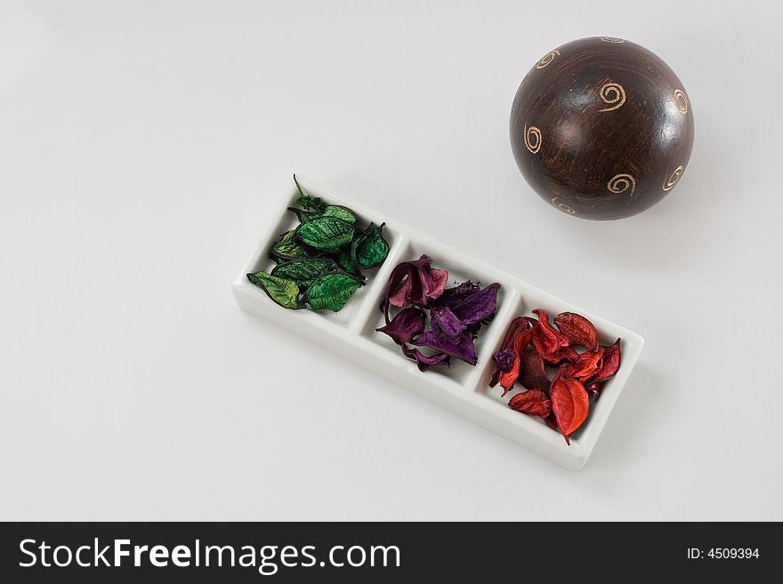 White ceramic decoration with colorful scented leafs and a wood ball isolated on white background. White ceramic decoration with colorful scented leafs and a wood ball isolated on white background.