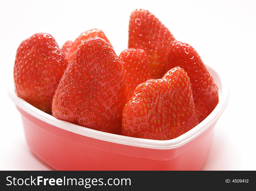 Few strawberries in the box in a shape of heart on white background. Few strawberries in the box in a shape of heart on white background