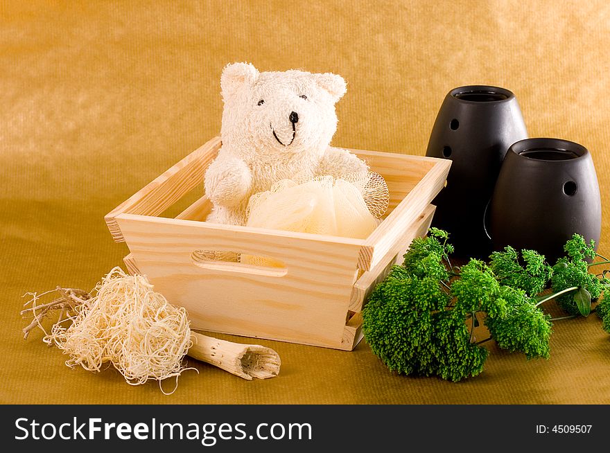 Wooden basket with bath items, a teddy bear, scented oil burners and an ornamental plant. Wooden basket with bath items, a teddy bear, scented oil burners and an ornamental plant.