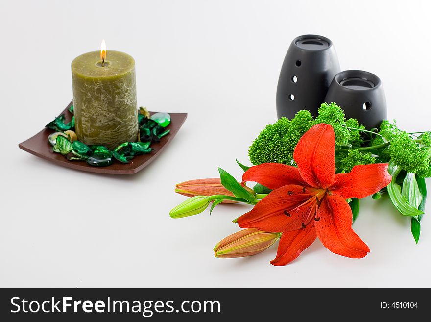 Red lily, green scented candle and black oil burner isolated on white background. Red lily, green scented candle and black oil burner isolated on white background.