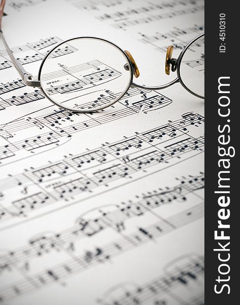 Old reading glasses resting on old sheet music. Old reading glasses resting on old sheet music