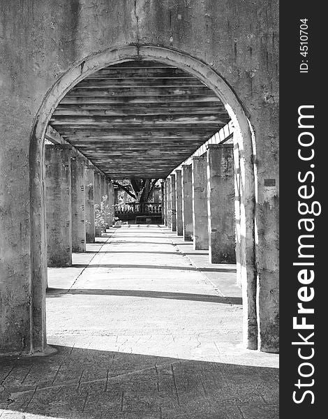 Black and white image of an old arched entrance to a pathway