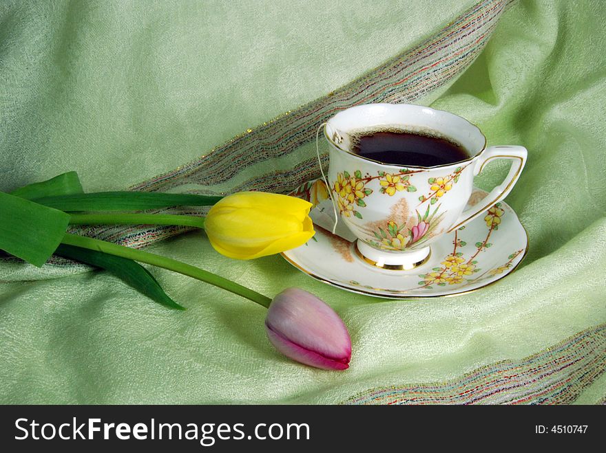 Delicate tea cup and spring tulips on linen. Delicate tea cup and spring tulips on linen.