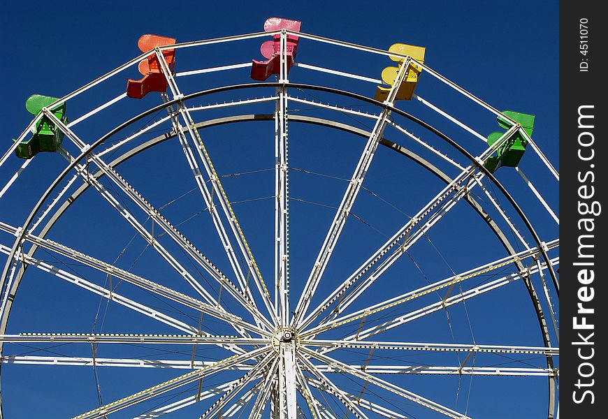 Colorful seats of the ferris wheel contrasted against a blue sky.