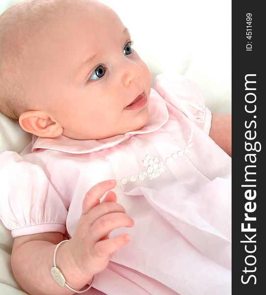 Smiling baby girl in pink dress on white comforter. Smiling baby girl in pink dress on white comforter