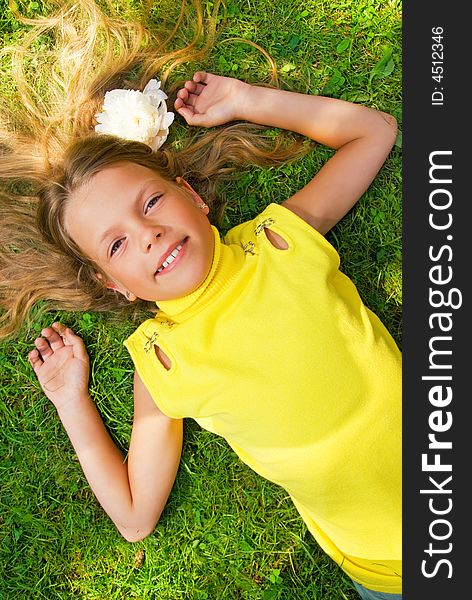 Happy young girl lying on a green grass