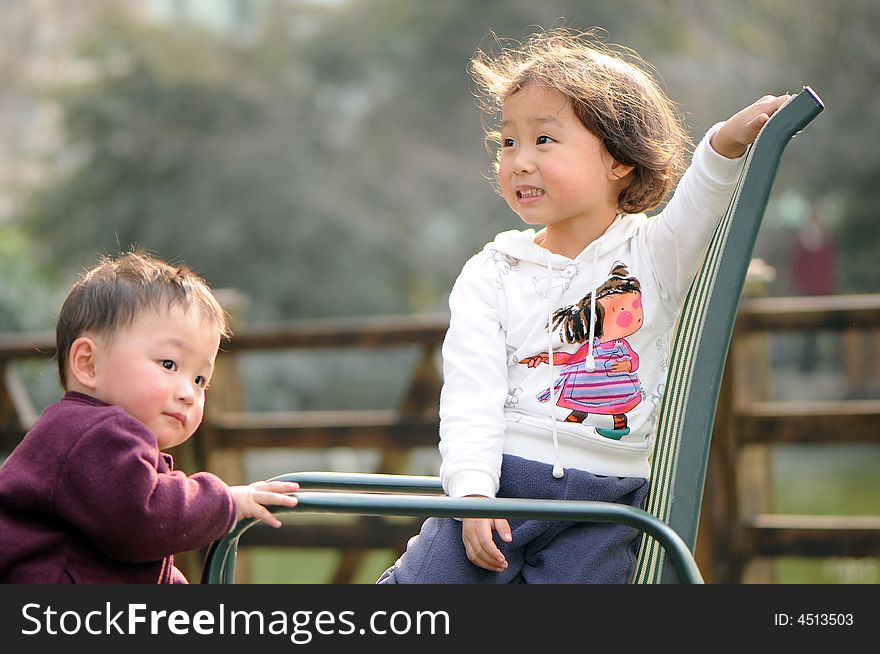 Little boy watchs his elder sister behind the chair. Little boy watchs his elder sister behind the chair.