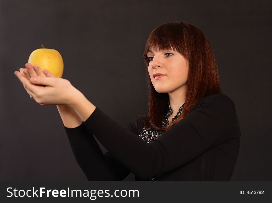 The red-haired girl holds an apple in hands. The red-haired girl holds an apple in hands