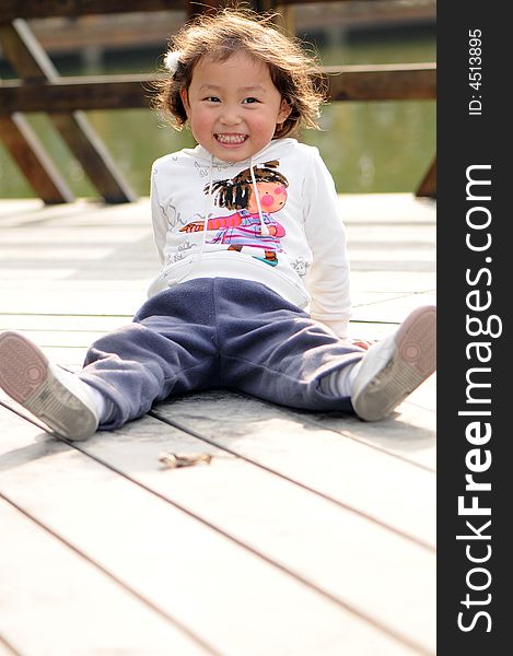 A little lovely girl sitting on the floor with a big smile.