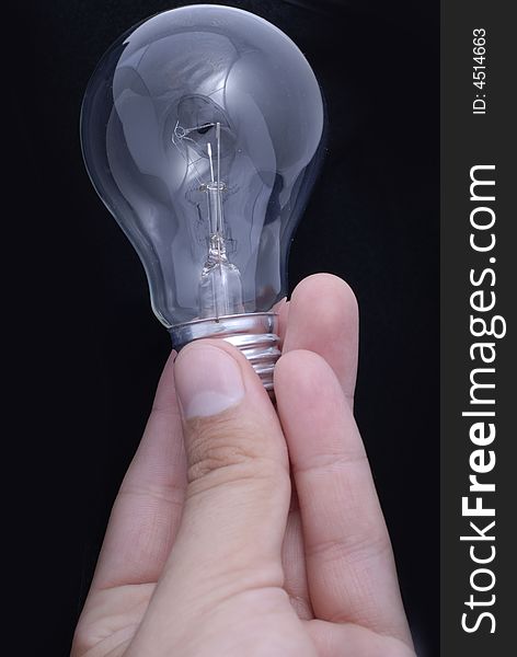 Bulb between the fingers on the black dark background. Bulb between the fingers on the black dark background