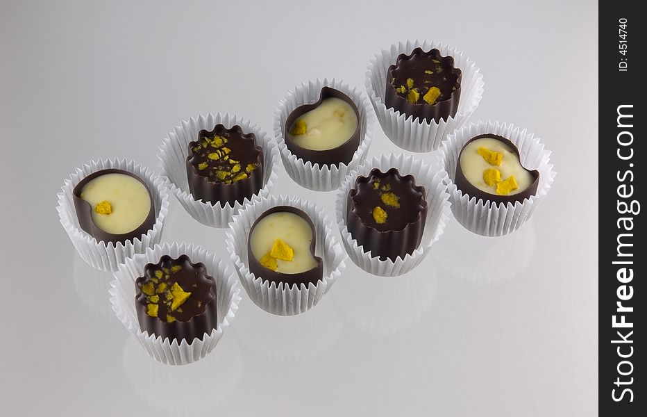 Chocolate candies from box, on glass. Light grey background.