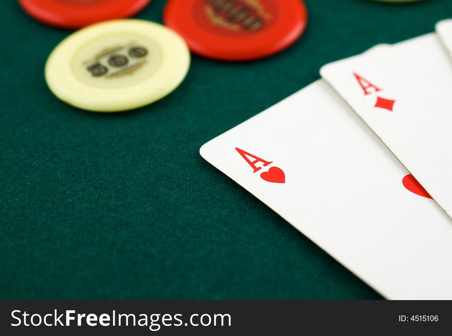 Aces and chips on green carpet with shallow depth of field