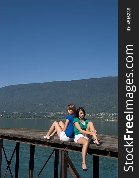 Young woman sitting on a pontoon at the edge of a lake. Young woman sitting on a pontoon at the edge of a lake