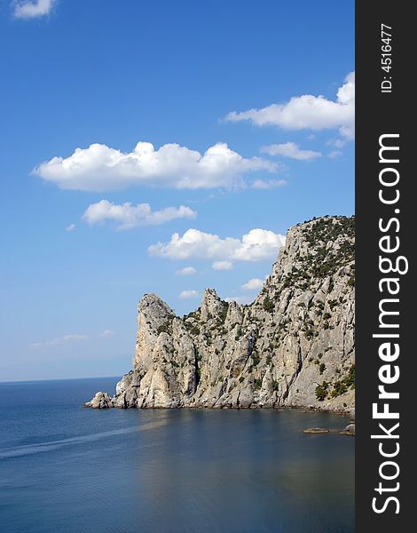 Rock on by sea, blue sky, clouds