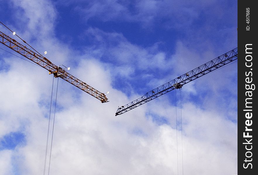 Two tower cranes on a background of the blue sky