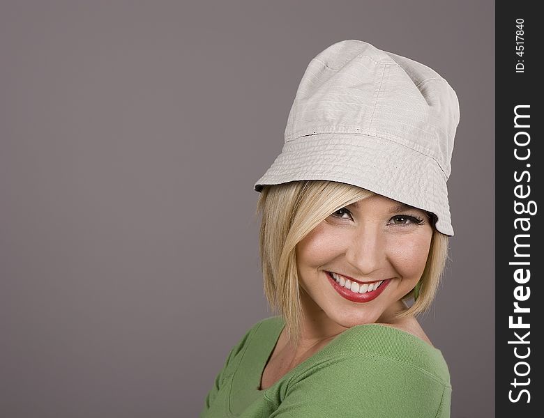 A blonde in a green blouse and silly white hat leaning back and smiling for the camera. A blonde in a green blouse and silly white hat leaning back and smiling for the camera