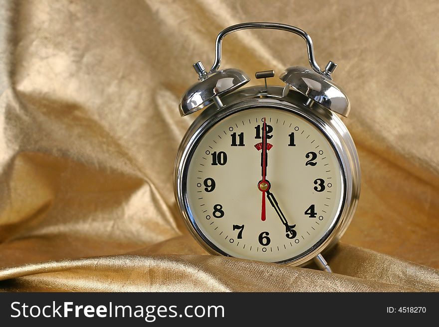 Metallic old-fashioned alarm-clock on gold background. Metallic old-fashioned alarm-clock on gold background