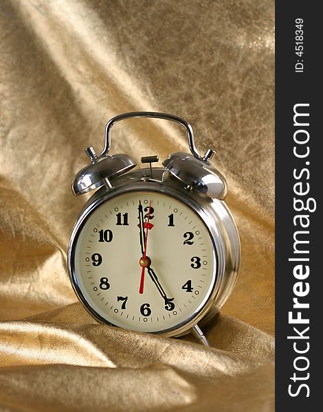 Metallic old-fashioned  alarm-clock on gold background. Metallic old-fashioned  alarm-clock on gold background