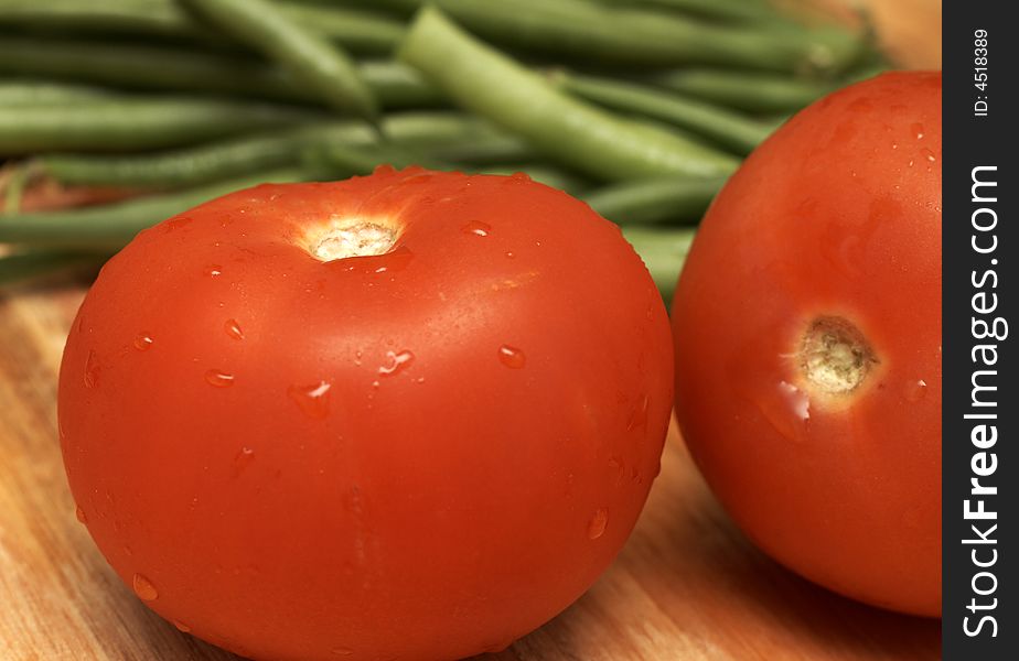 Juicy fresh red tomatoes and green beans on wooden board. Juicy fresh red tomatoes and green beans on wooden board