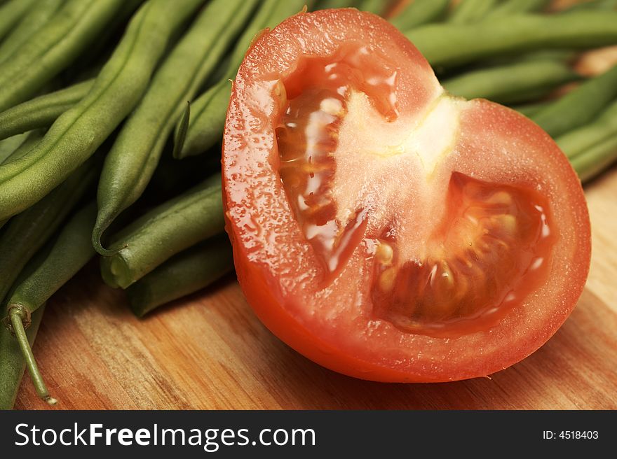 Juicy fresh sliced red tomato and green beans on wooden board. Juicy fresh sliced red tomato and green beans on wooden board