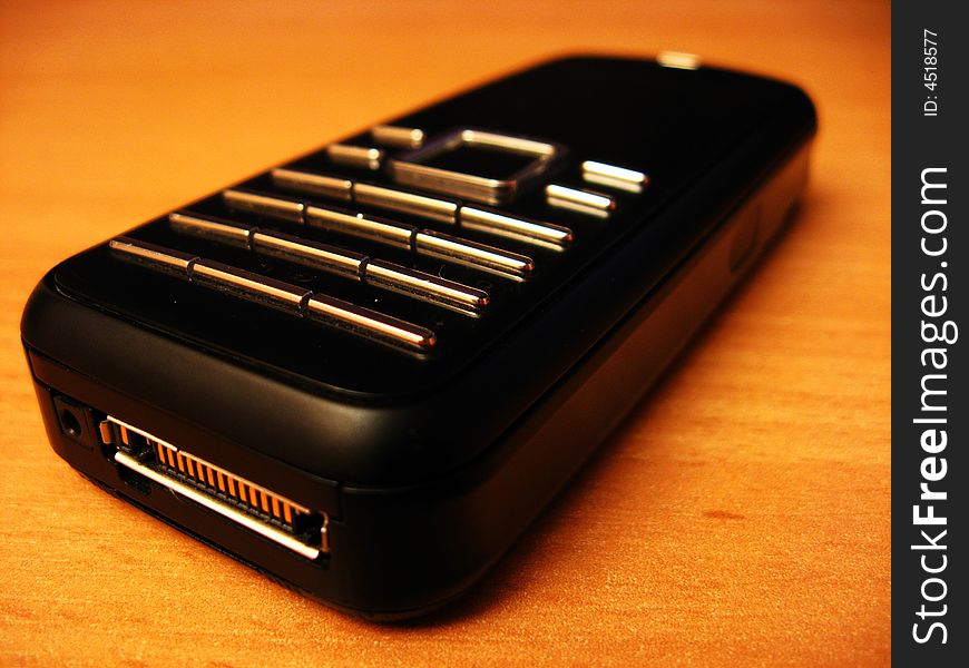 Black plastic mobile phone on a wooden desk