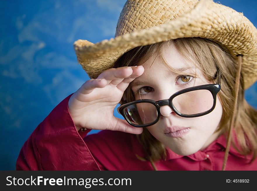 Little girl wearing a straw cowboy hat adjusts her glasses. Little girl wearing a straw cowboy hat adjusts her glasses