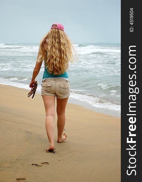 A Young Woman Walks Alone On The Beach