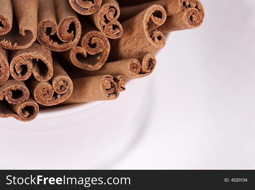 Close-up of a coffee cup filled with cinnamon sticks on white background