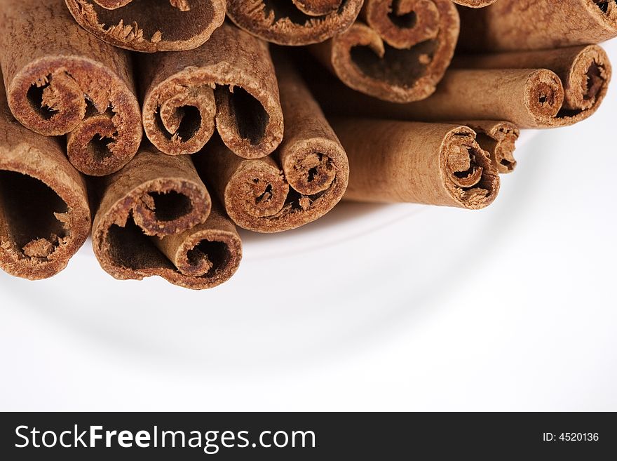 Close-up of a coffee cup filled with cinnamon sticks on white background